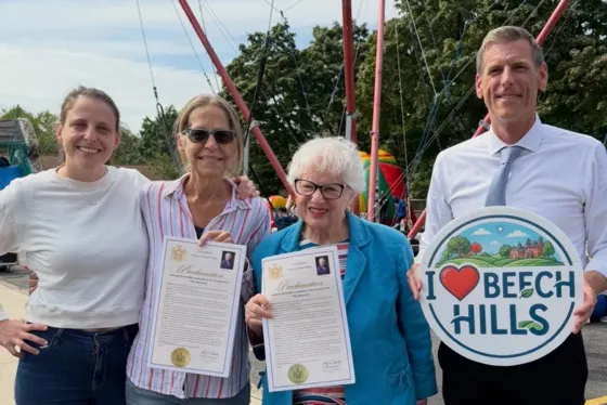 Jane Menton, Janice Schreibersdorf, Senator Toby Stavisky, and Assemblymember Ed Braunstein with proclamations and an I Love Beech Hills sign at the block party